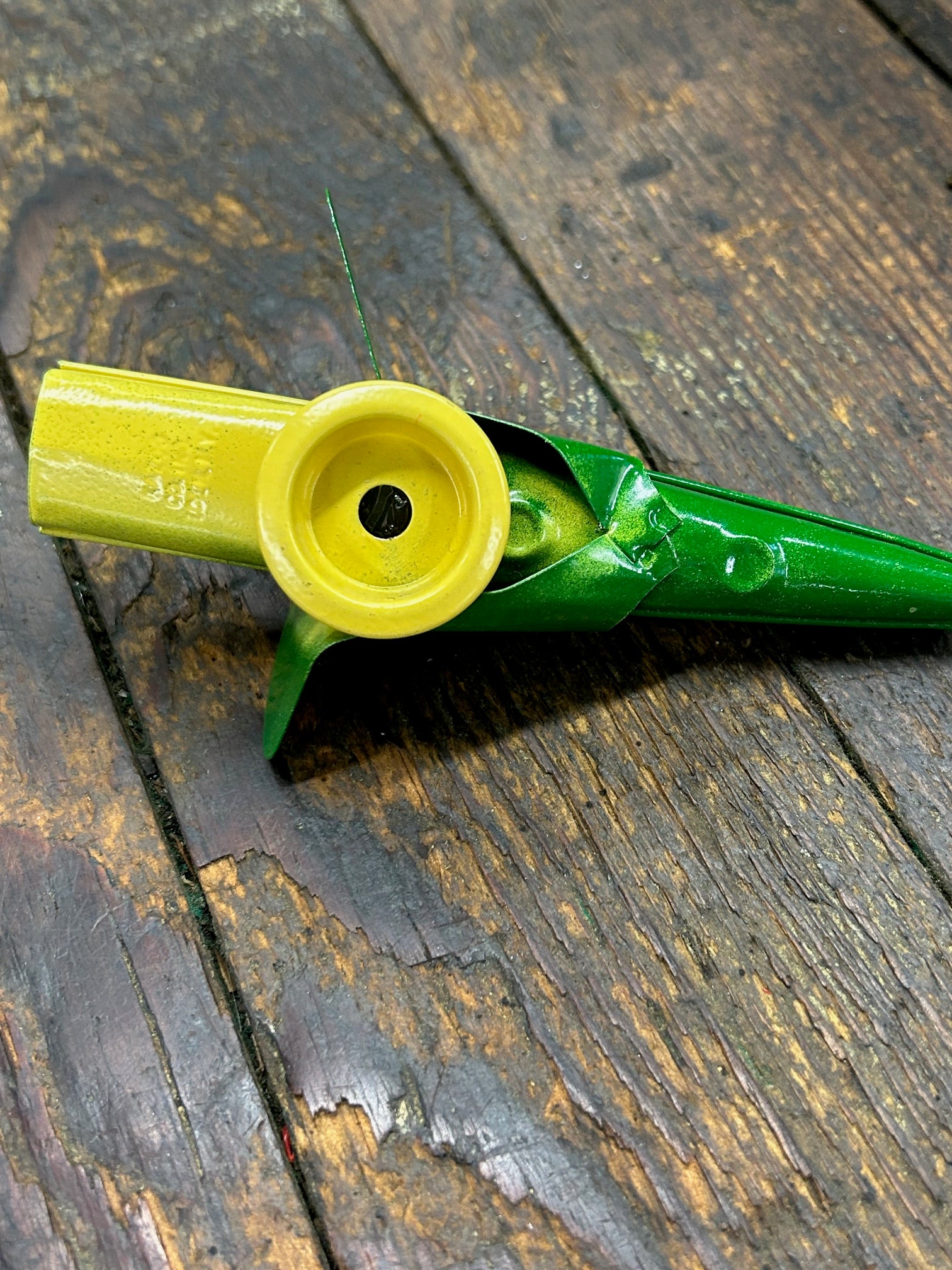 A green and yellow metal kazoo designed to look like a ear of corn.